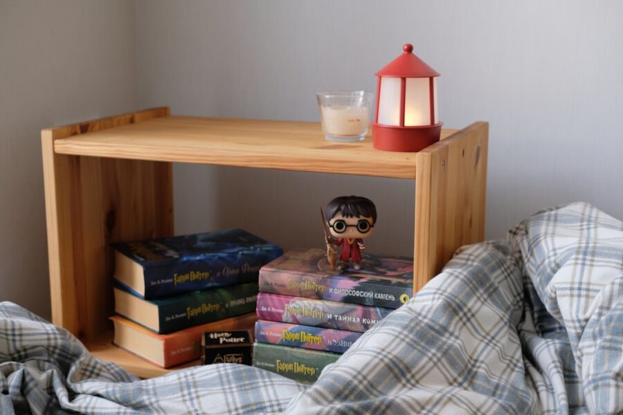 a stack of books sitting on top of a bed next to a lamp