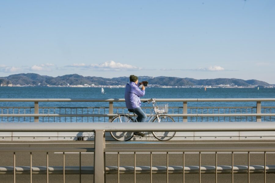 Person riding bicycle on a bridge with ocean view