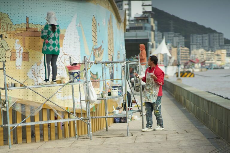Artist painting outdoor mural scaffold children helping paint