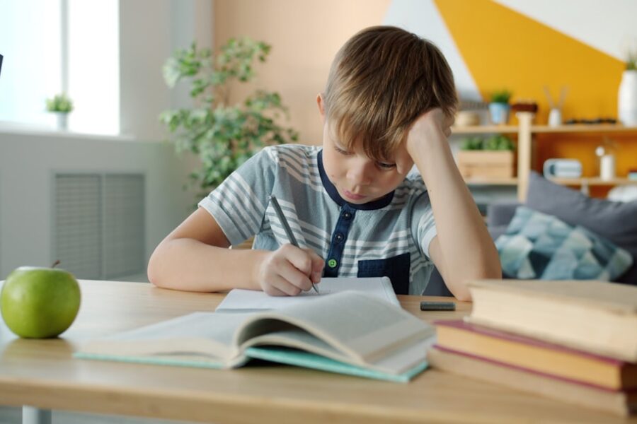 Young boy concentrating while doing homework at desk.