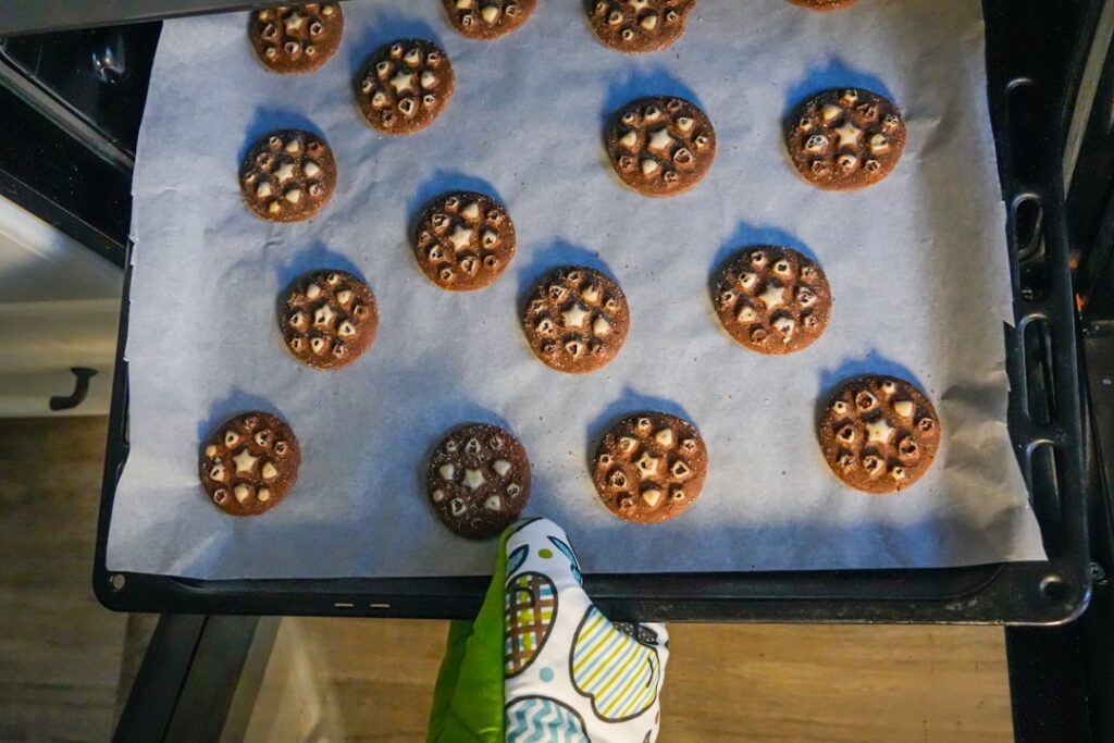 Chocolate cookies with white centers on baking sheet.