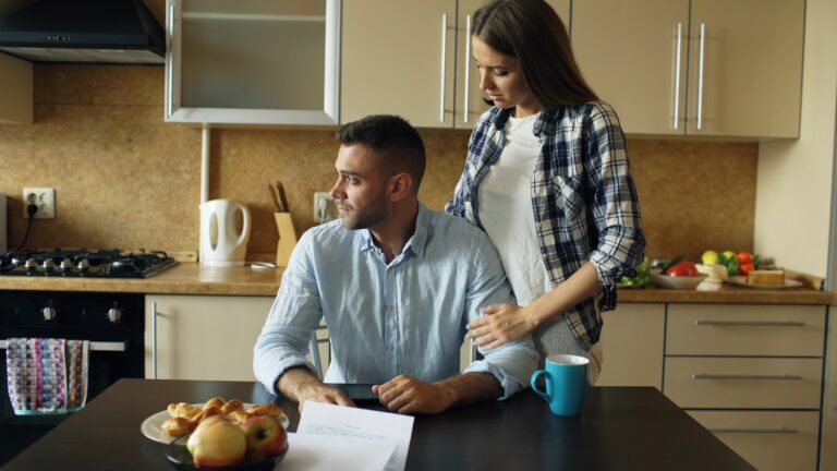 Laptop bank statements budgeting couple kitchen table paying