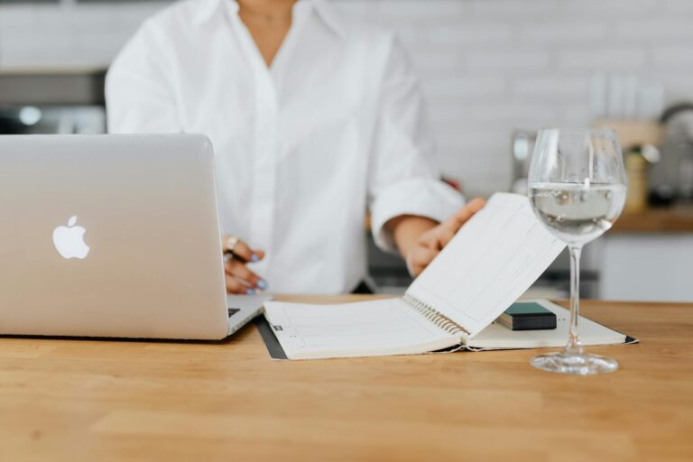 Woman sitting desk massaging temples laptop water glass