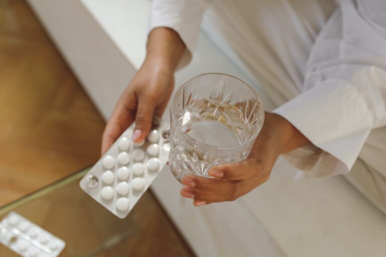 Close hand holding glass water pills person stretching