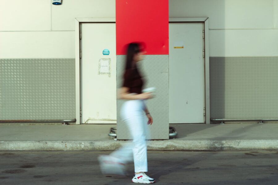 Woman walking city street headphones sneakers