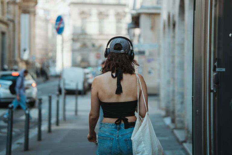 Woman walking city street headphones sneakers