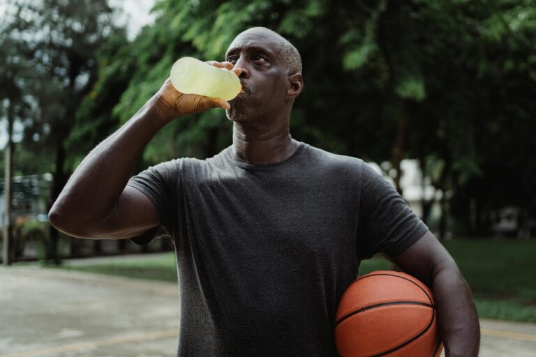 Basketball player drinking sports drink bench